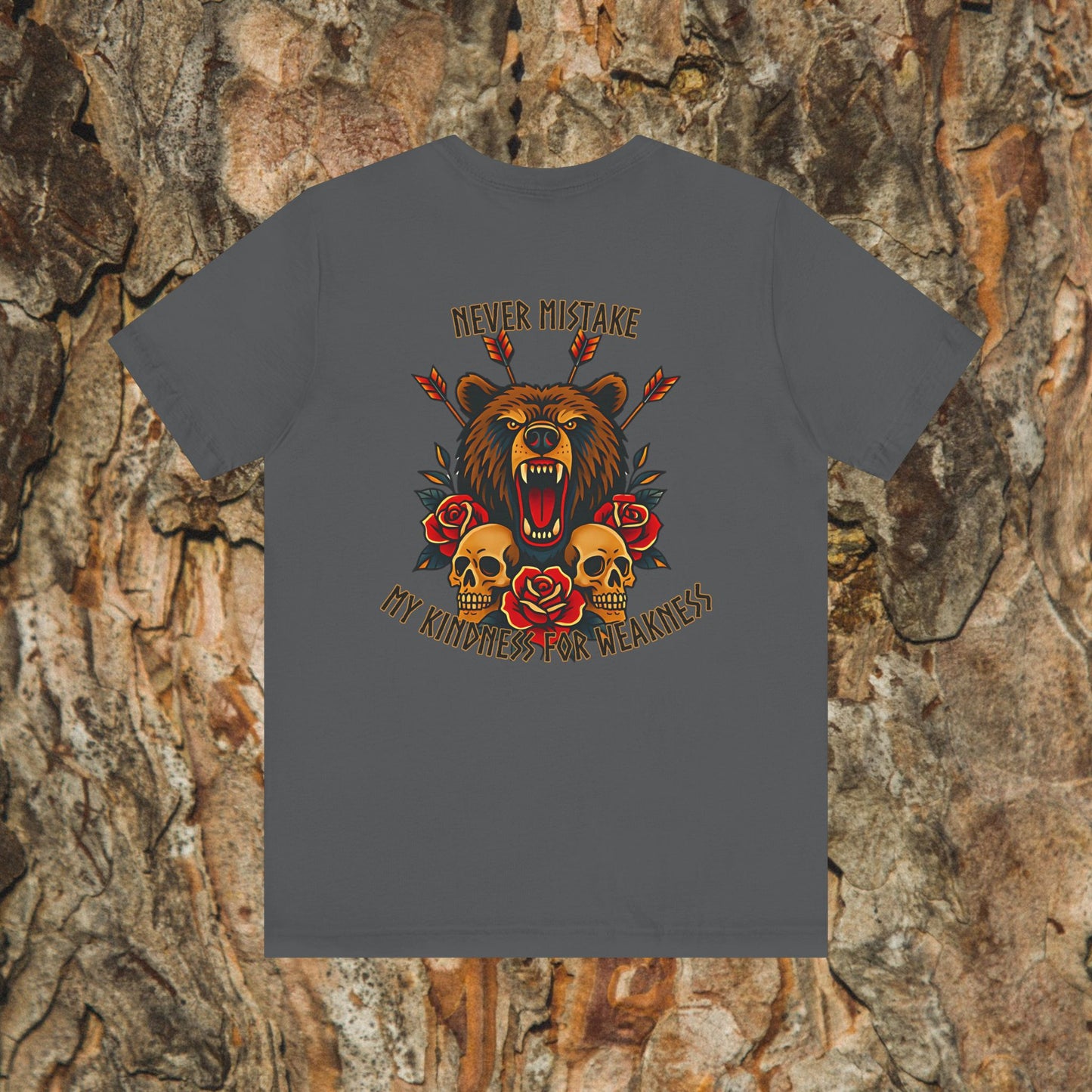 The Never Mistake My Kindness For Weakness Tee by Printify is a gray unisex graphic t-shirt with a roaring bear, arrows, skulls, and red roses on soft Airlume cotton. Displayed against tree bark, it features the bold motto on the front.