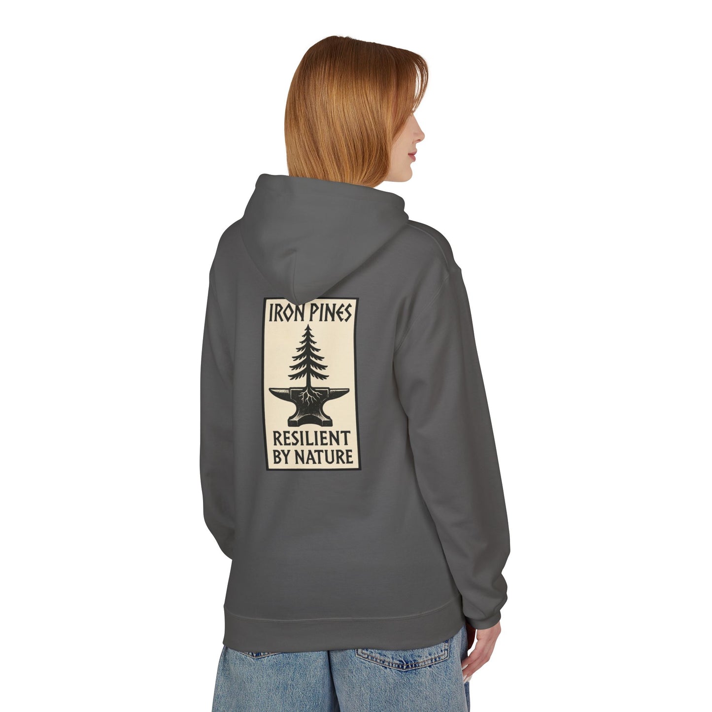 A person with straight, light brown hair wears The Iron Pines Hoodie by Printify—a gray midweight fleece with a pine tree graphic and “RESILIENT BY NATURE” on the back—paired with blue jeans, highlighting sustainable outdoor style. Seen from behind.