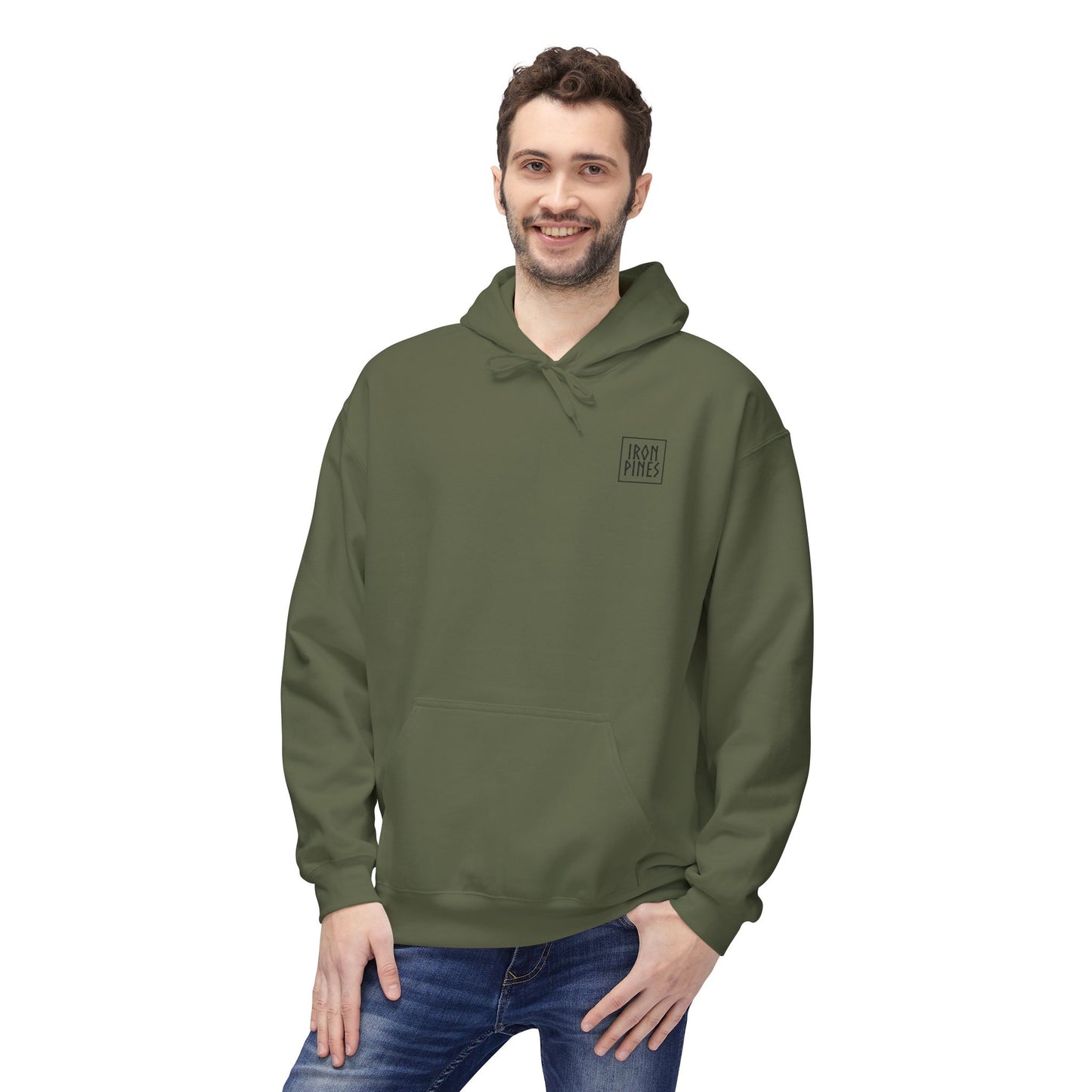 A smiling man with brown hair and a beard wears The Iron Pines Hoodie by Printify in olive green, featuring “Iron Pride” on the chest, midweight fleece material, and pairs it with blue jeans. He stands against a plain white background.