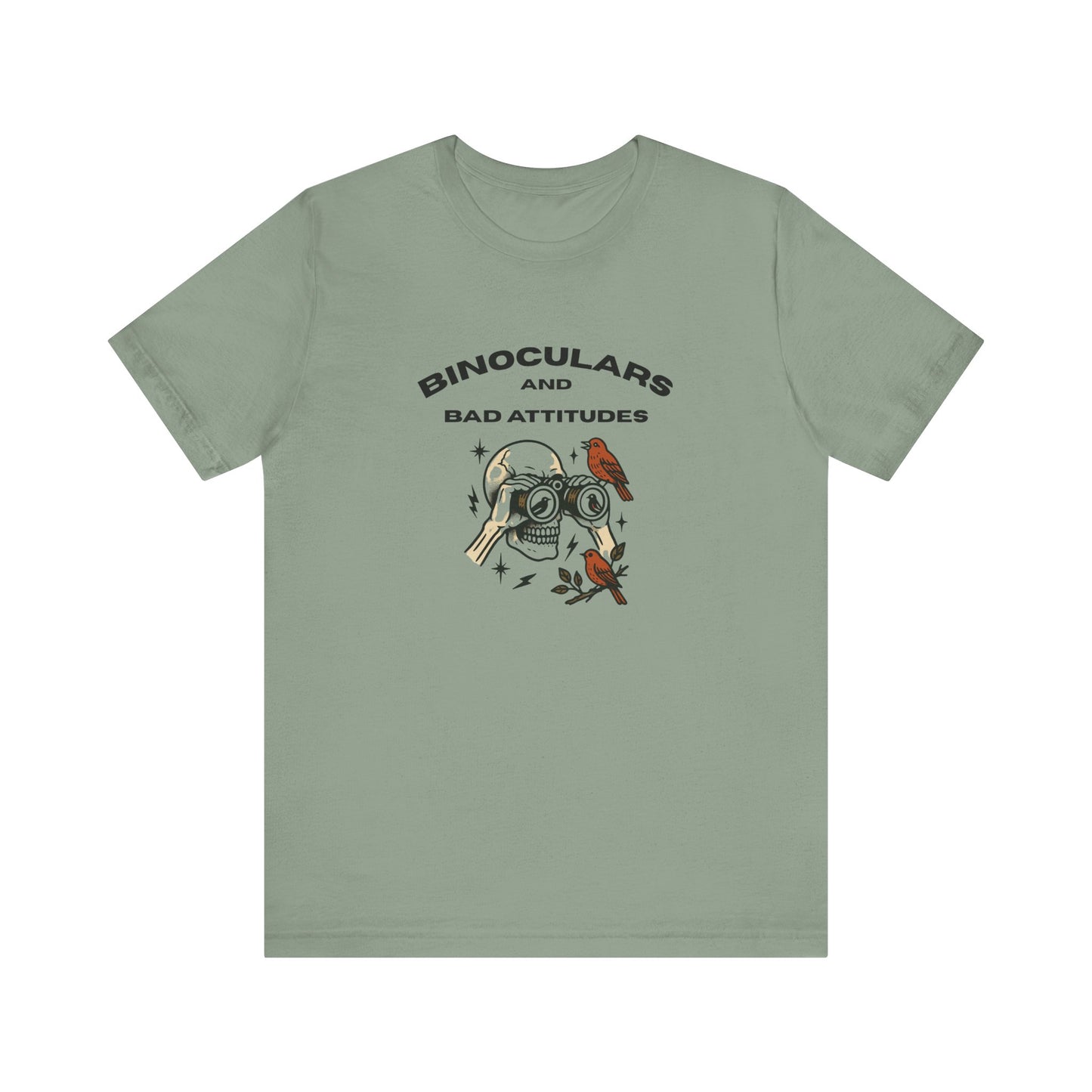 The Bird Watching Is Hardcore T-Shirt by Printify features a sage green design with binoculars, a red bird, and stars, plus bold BINOCULARS AND BAD ATTITUDES text—perfect for punk rocker birders and shirt collectors.