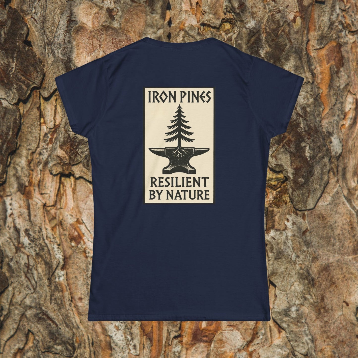 The Iron Pines Woman’s Tee by Printify features a navy blue softstyle design with a pine tree graphic growing from an anvil and the phrase resilient by nature, blending comfort and nature-inspired style.