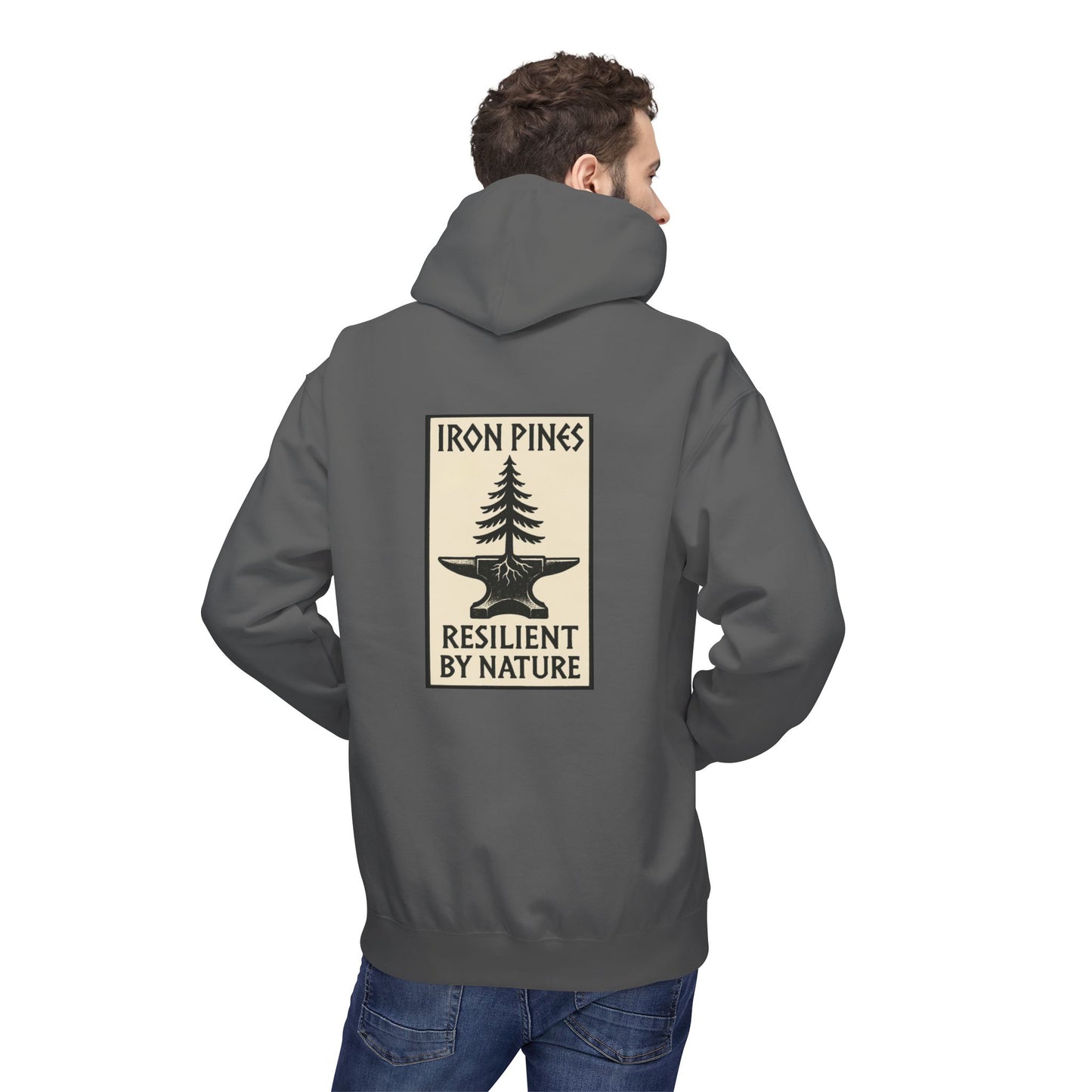 A man wears The Iron Pines Hoodie by Printify—a gray midweight fleece with a back graphic of a tree growing from an anvil and the words Iron Pines Resilient by Nature, ideal for fans of sustainable outdoor apparel.