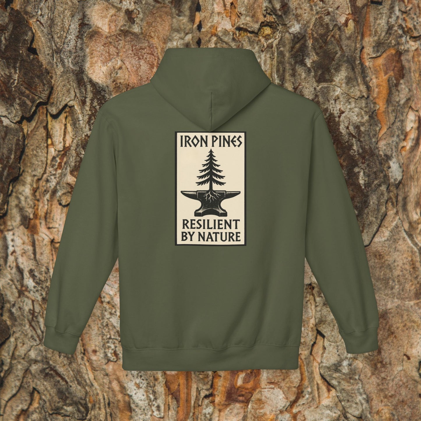 The Iron Pines Hoodie by Printify is an olive green, sustainable outdoor hoodie with a pine tree and anvil patch on the back, IRON PINES above, and RESILIENT BY NATURE below. Shown against a tree bark background.