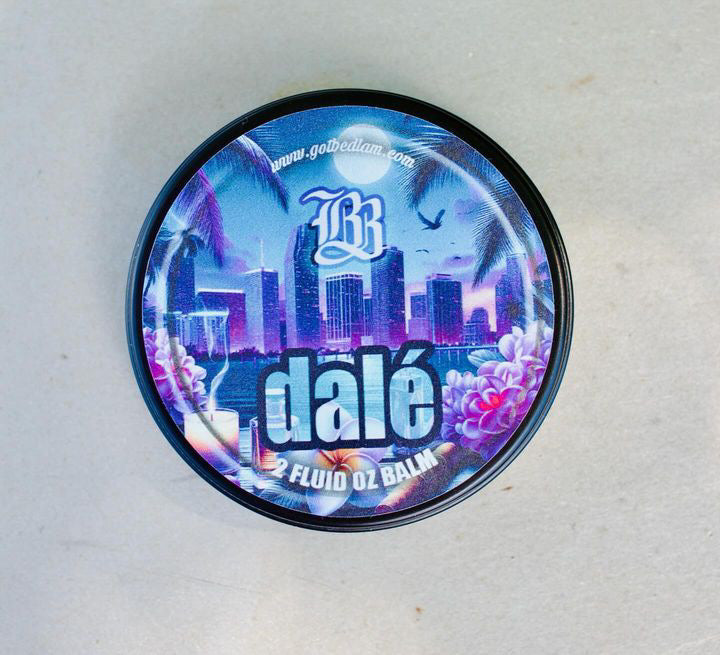 A round container labeled DALÉ Beard Oil & Balm by Bedlam Beard Company shows a tropical cityscape, palm trees, purple flowers, and an hourglass on the lid—perfect for any beard kit. www.gobledam.com is displayed at the top.