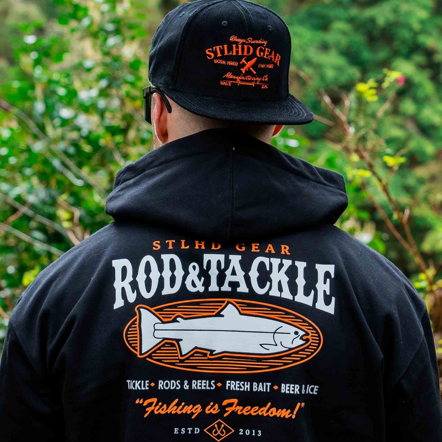 Person wearing a black hoodie and cap with 'STLHD GEAR' Rod & Tackle branding, standing outdoors.