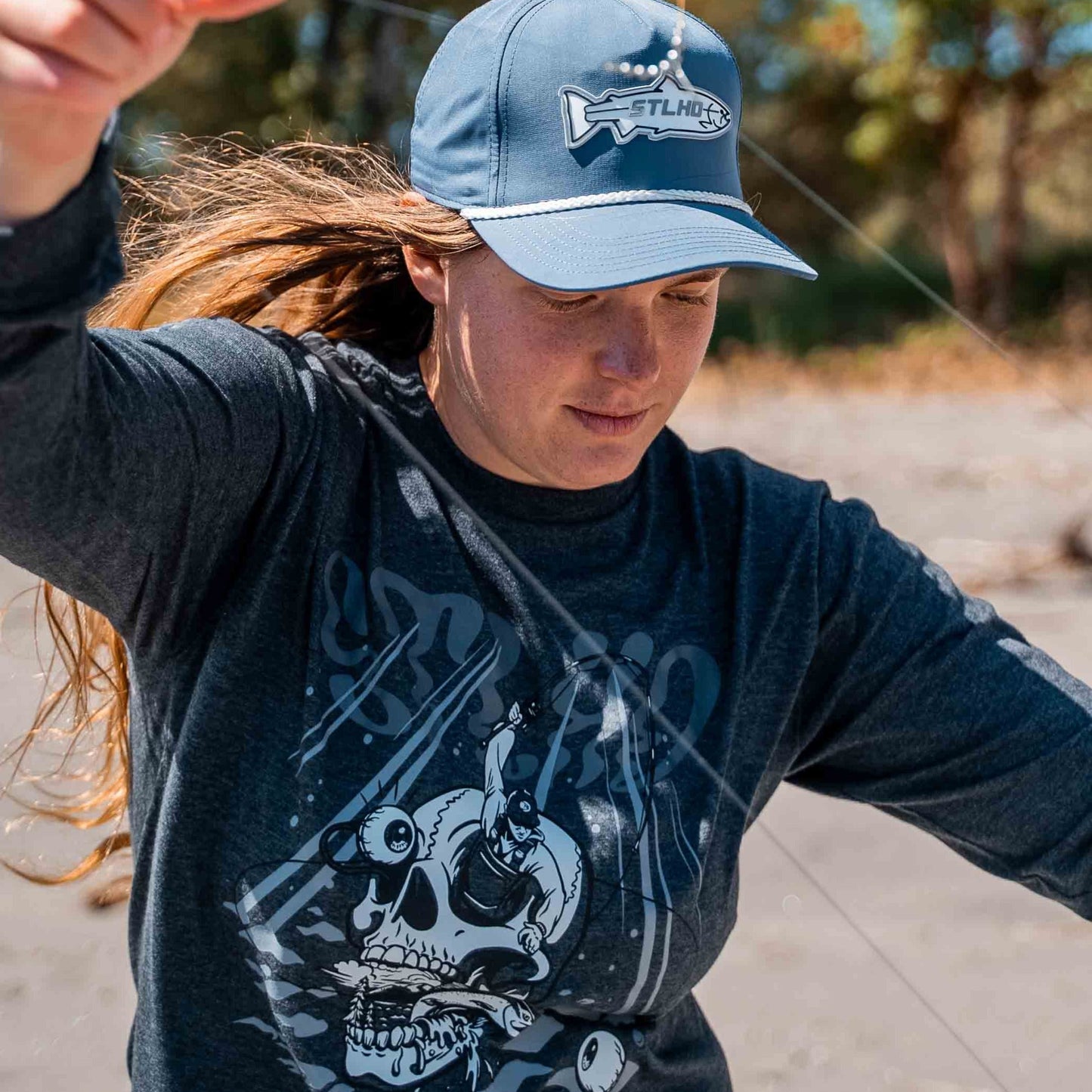 Person wearing a blue cap and black shirt with a skull design outdoors