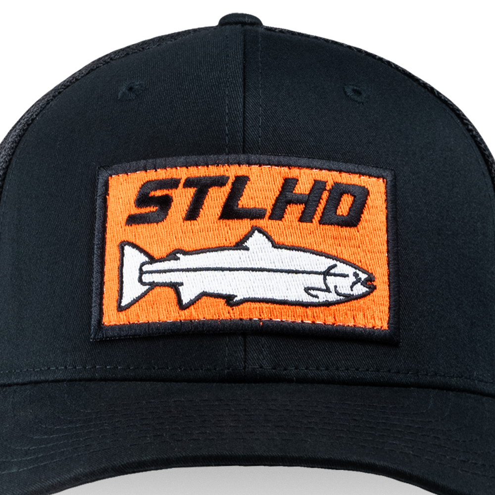 The STLHD GEAR Beaver State Flex Fit Trucker Hat is black with an orange and black patch showing “STLHD Beaver State” above a white, black-outlined fish illustration.