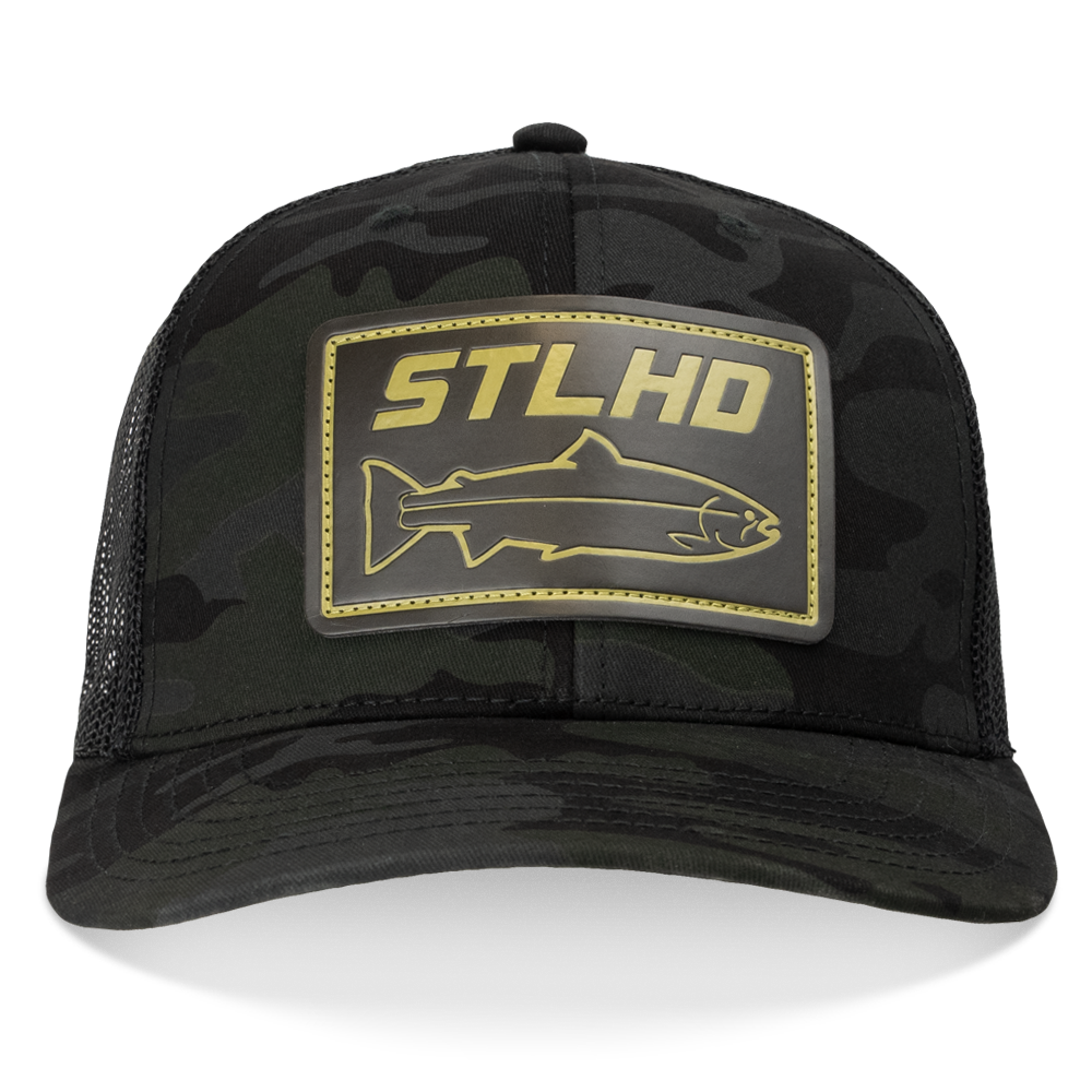 The STLHD GEAR Black Ops Multicam Snapback Trucker Hat features black camo with mesh panels, an adjustable snapback, and a gold front patch displaying “STLHD” in bold above a fish outline.