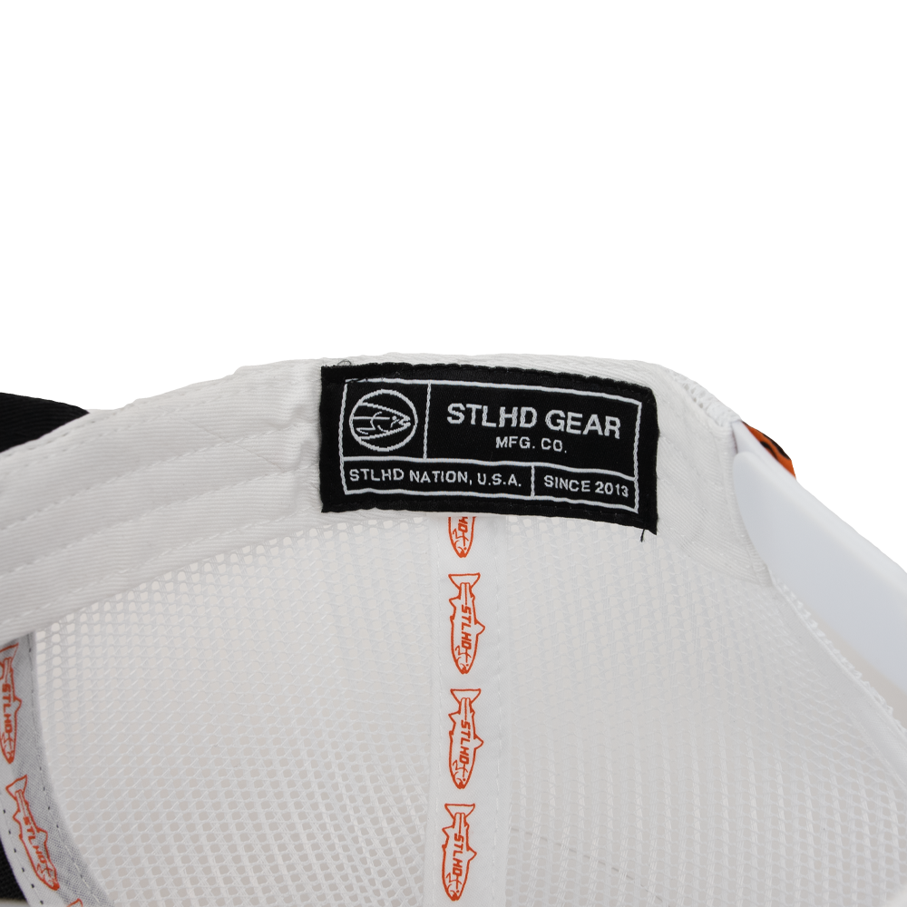 Close-up of the STLHD Standard White & Black Trucker Hat by STLHD GEAR, showing its black brand label and orange fish symbols along the inner seam of this adjustable snapback trucker hat.