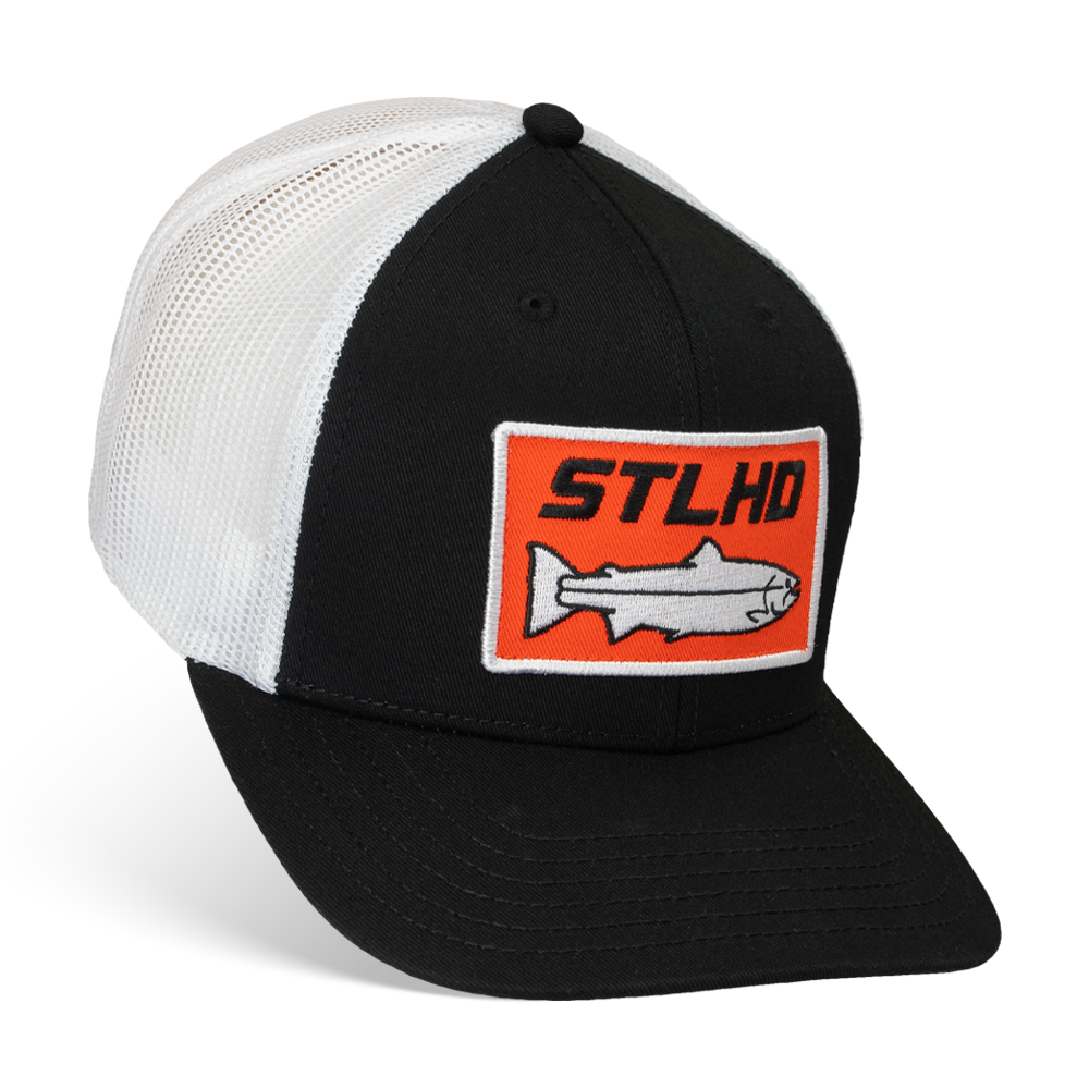 The STLHD GEAR Standard White & Black Trucker Hat features a mesh back, adjustable snapback, and a front patch with an orange rectangle, fish graphic, and STLHD text.