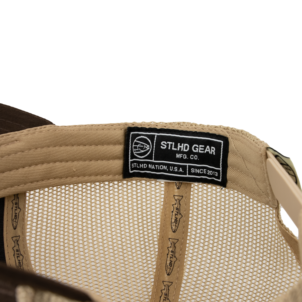 Close-up of the STLHD Steelhide Brown/Khaki Hat by STLHD GEAR, featuring a black label with logo, fish designs on the inner band, and an adjustable snapback for comfort.