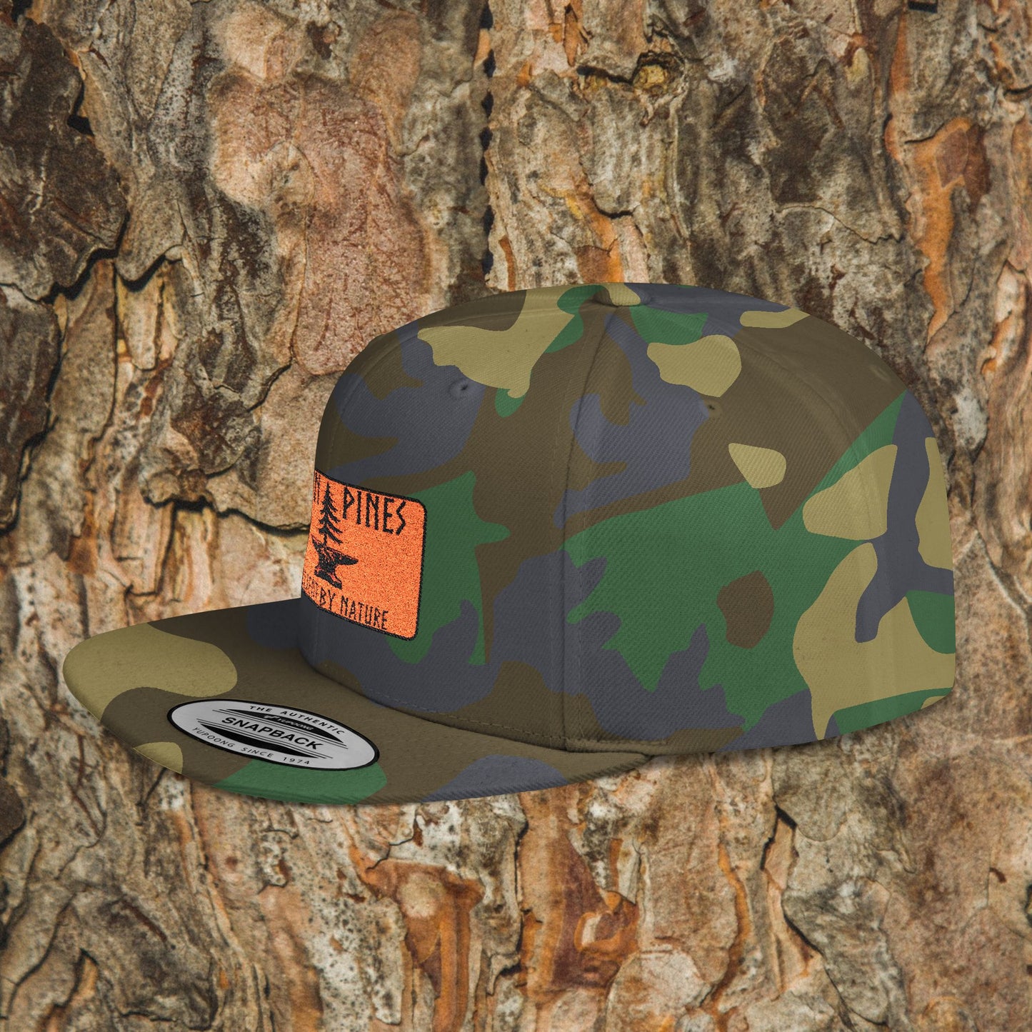 The Iron Pines Logo Hat by Printify features an embroidered logo on a camouflage snapback, accented with a bright orange Pine patch that stands out against natural backgrounds.