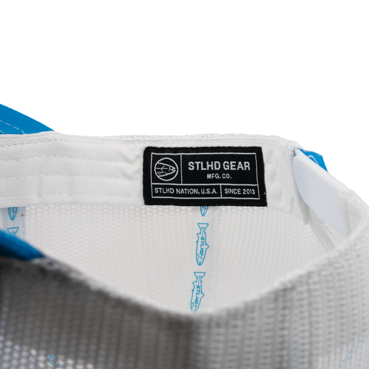 Close-up of a white shirt with a black label reading 'STLHD GEAR MFG. CO.' on a white background.