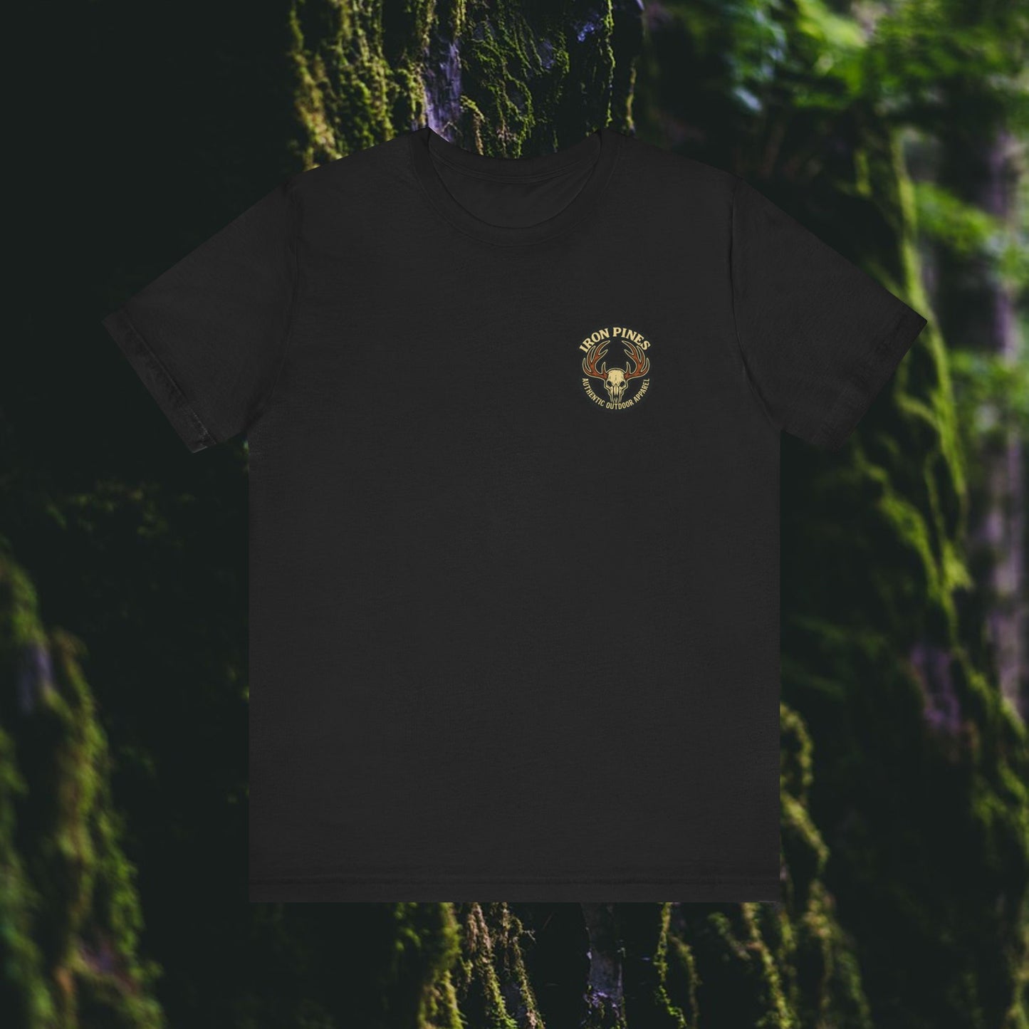 The I Hunt Because Bail’s Expensive Tee by Printify is a durable black outdoor shirt, featuring a small round Twin Pines logo with a pine tree graphic on the left chest, set against a blurred mossy forest background.