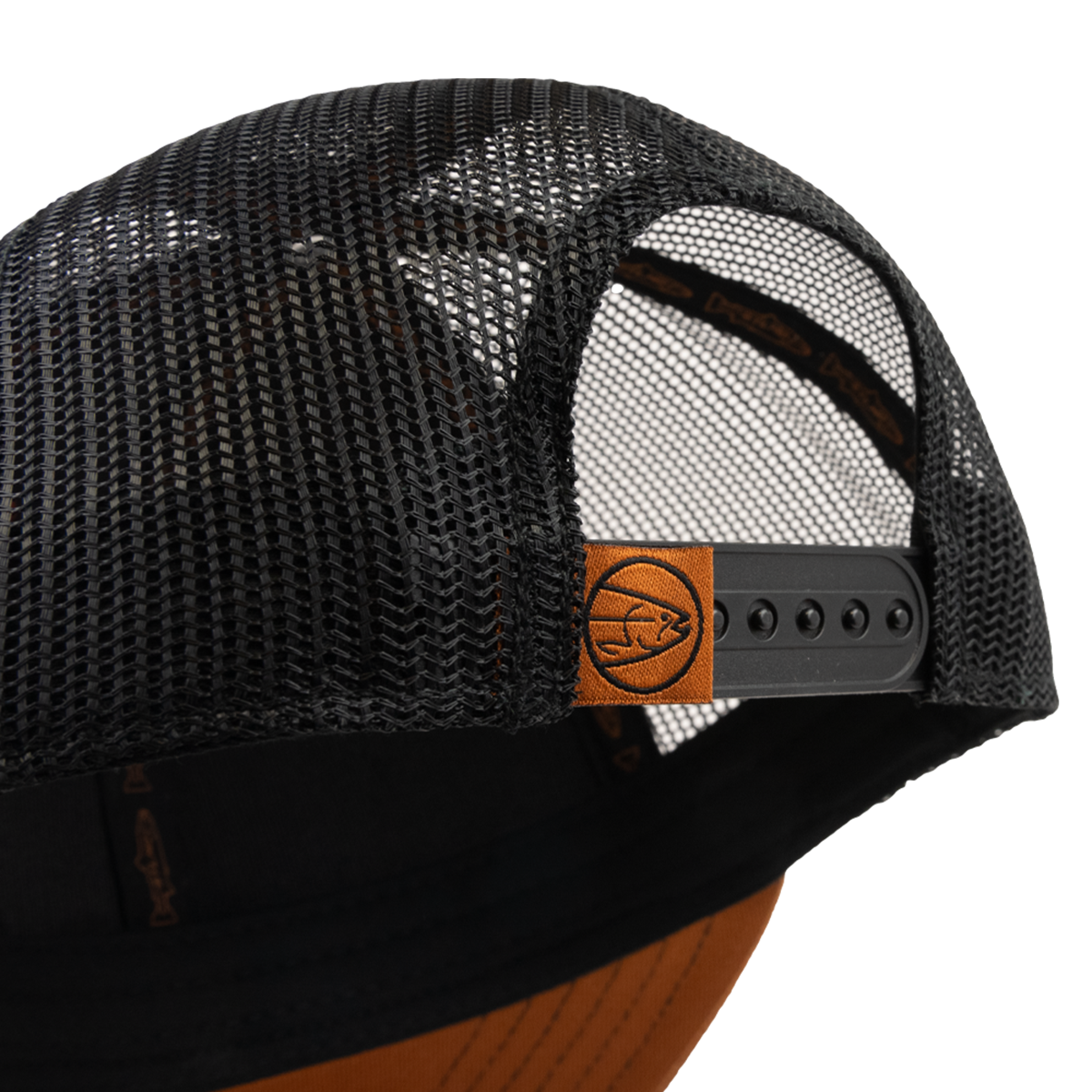 Close-up of the STLHD GEAR Hook X Hammer Trucker Hat—a black mesh trucker with adjustable snapback and a brown leather patch featuring a fish logo.