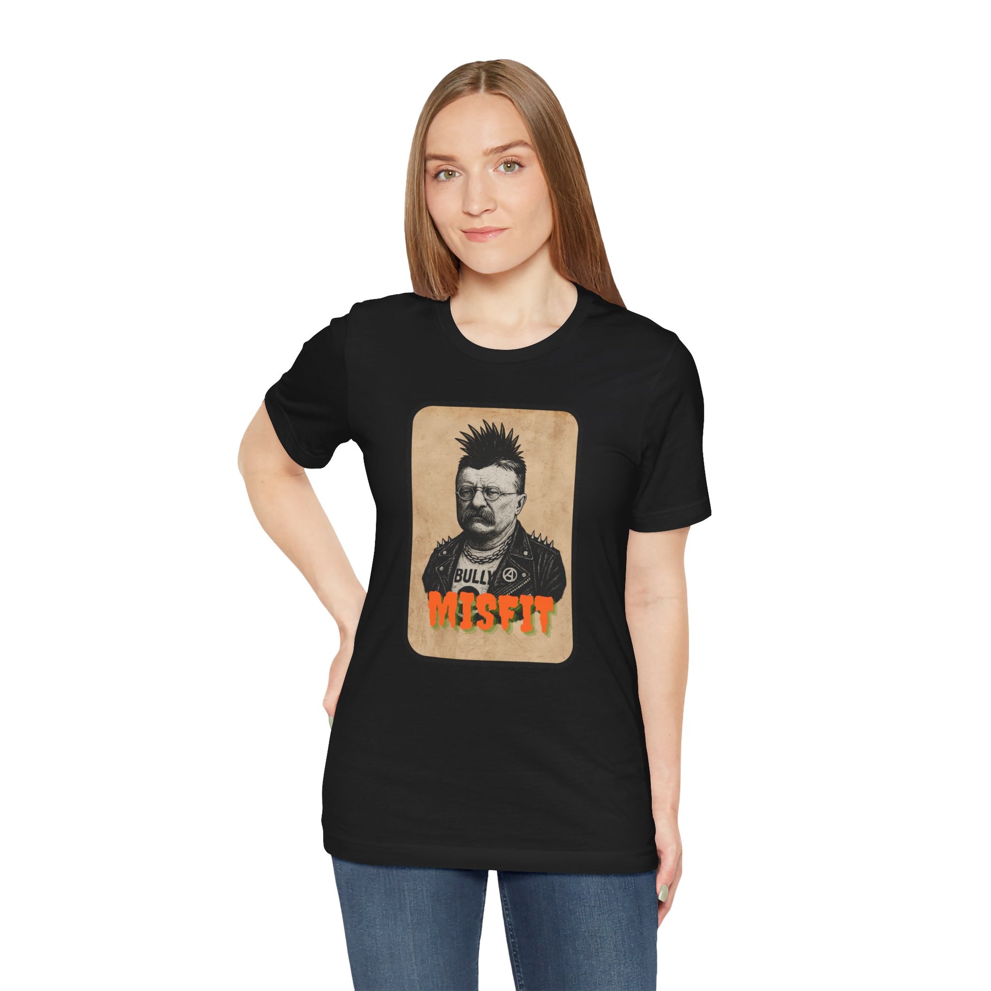 A woman with straight light brown hair wears the Iron Pines Teddy Roosevelt Punk T-Shirt, featuring a serious, spiky-haired Teddy labeled “Bully” and “MISFIT.” She stands against a plain white background.