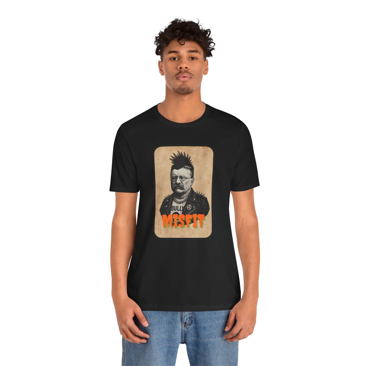 A young man with curly hair wears the Iron Pines Teddy Roosevelt Punk T-Shirt, a black Misfit History tee featuring a vintage-style image of punk Roosevelt and Bully Misfit in bold lettering.