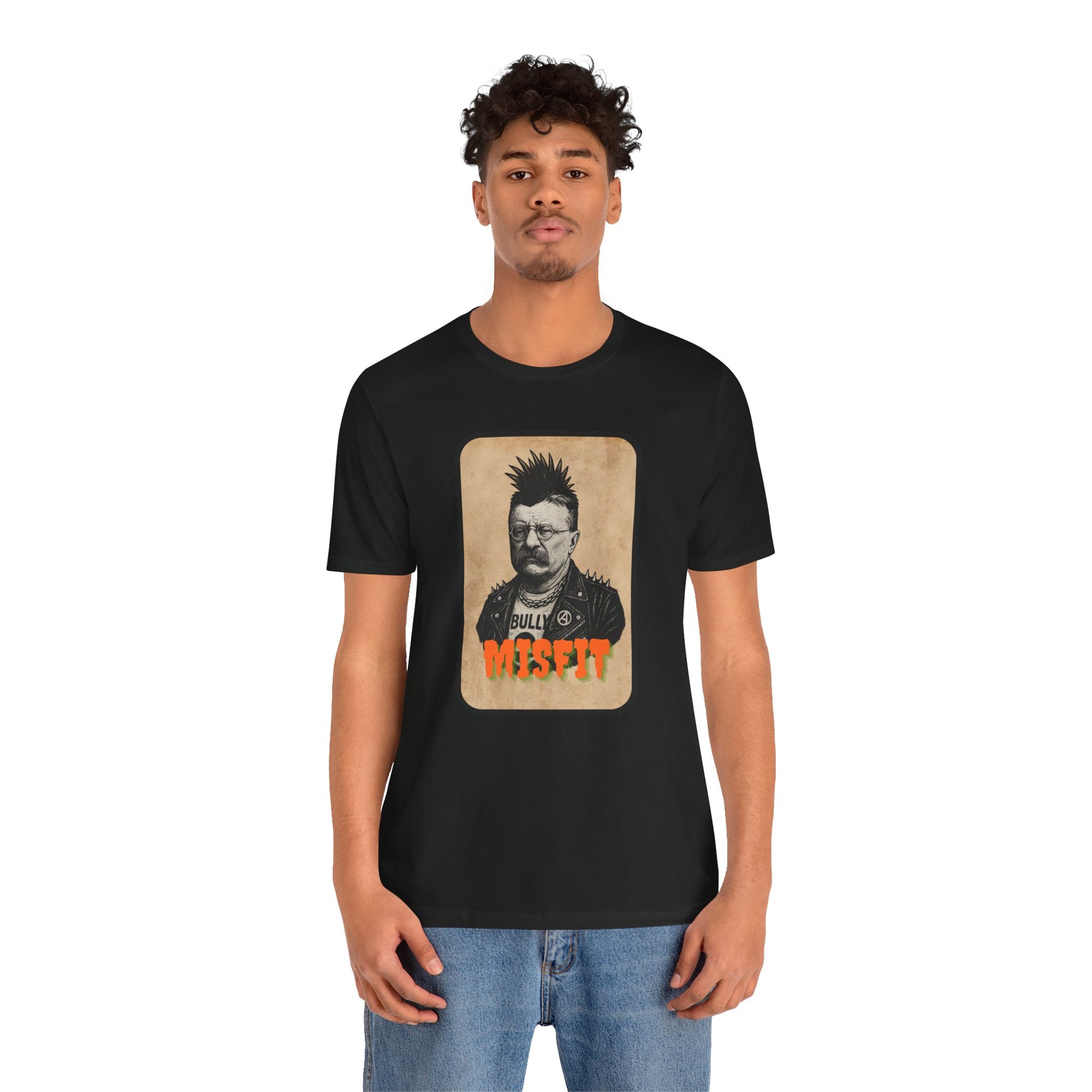 A young man with curly hair wears the Iron Pines Teddy Roosevelt Punk T-Shirt, a black Misfit History tee featuring a vintage-style image of punk Roosevelt and Bully Misfit in bold lettering.