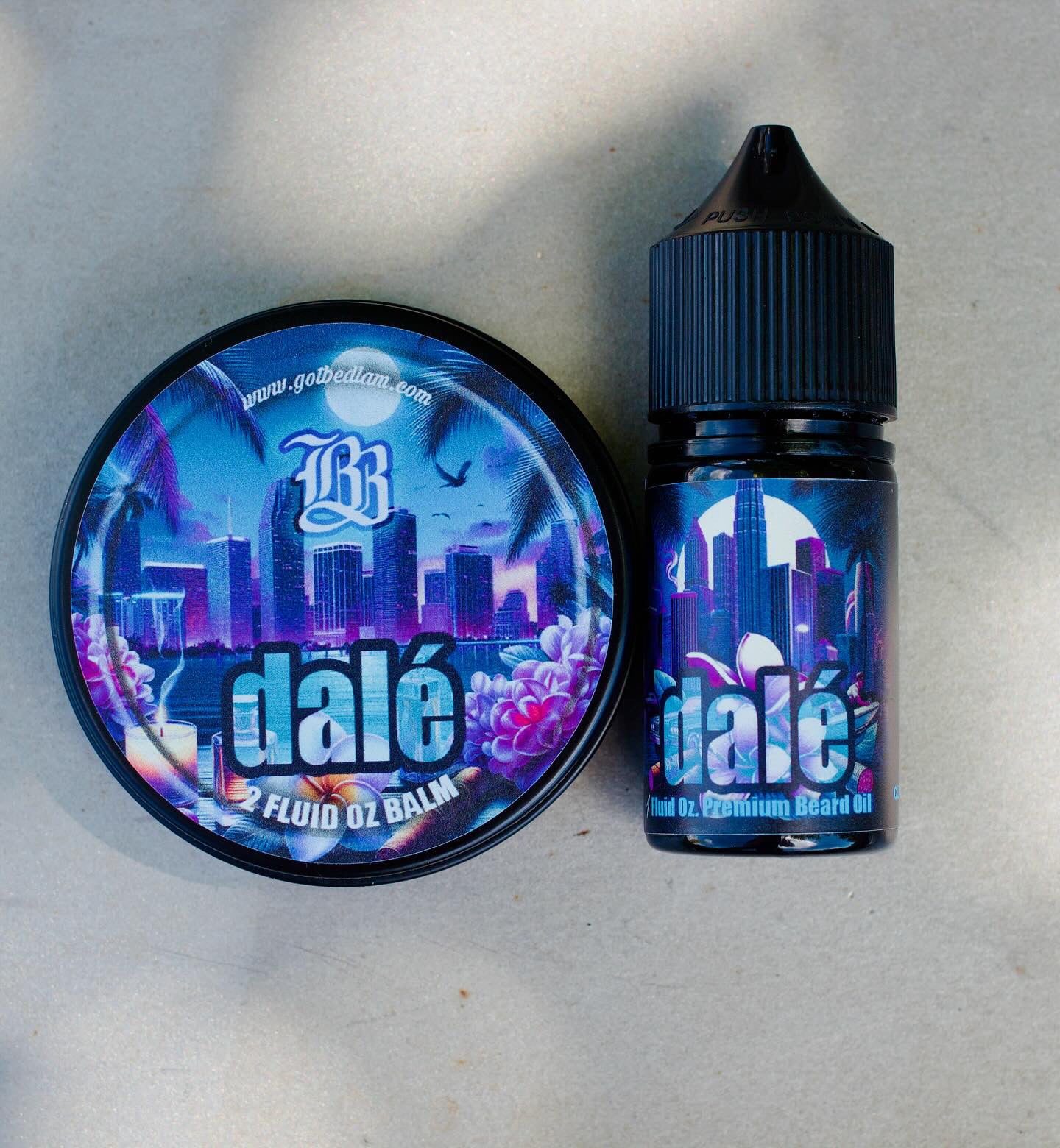 A round tin of DALÉ Beard Balm and a small bottle of DALÉ Beard Oil by Bedlam Beard Company, both with blue and purple labels featuring a city skyline, palm trees, and dalé, rest on a light surface.