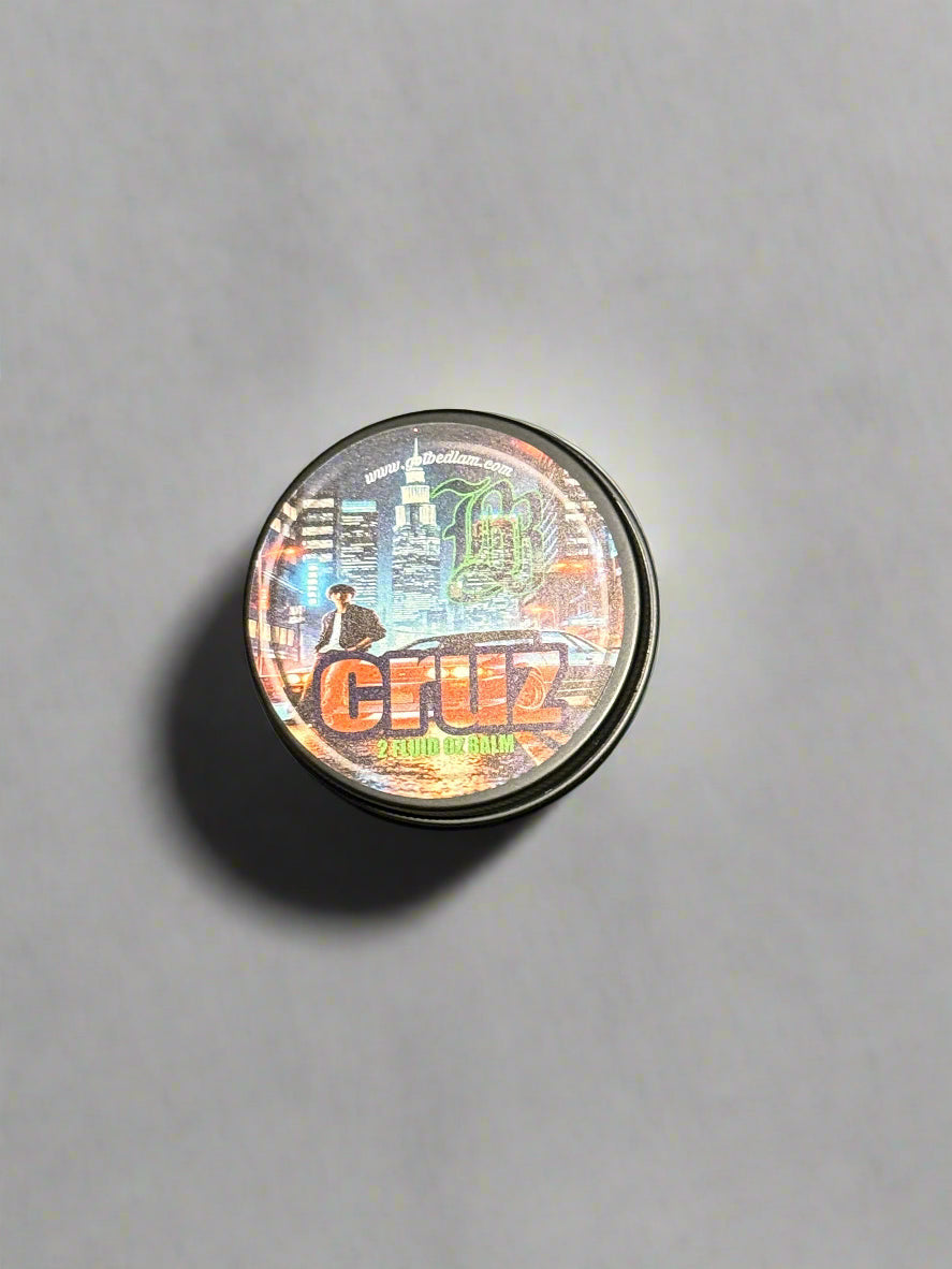 A small round tin with a holographic label featuring a city skyline, a dog, and the text CRUZ Beard Oil & Balm by Bedlam Beard Company sits on a plain light gray surface—its scent hints at forest oud and subtle musk.