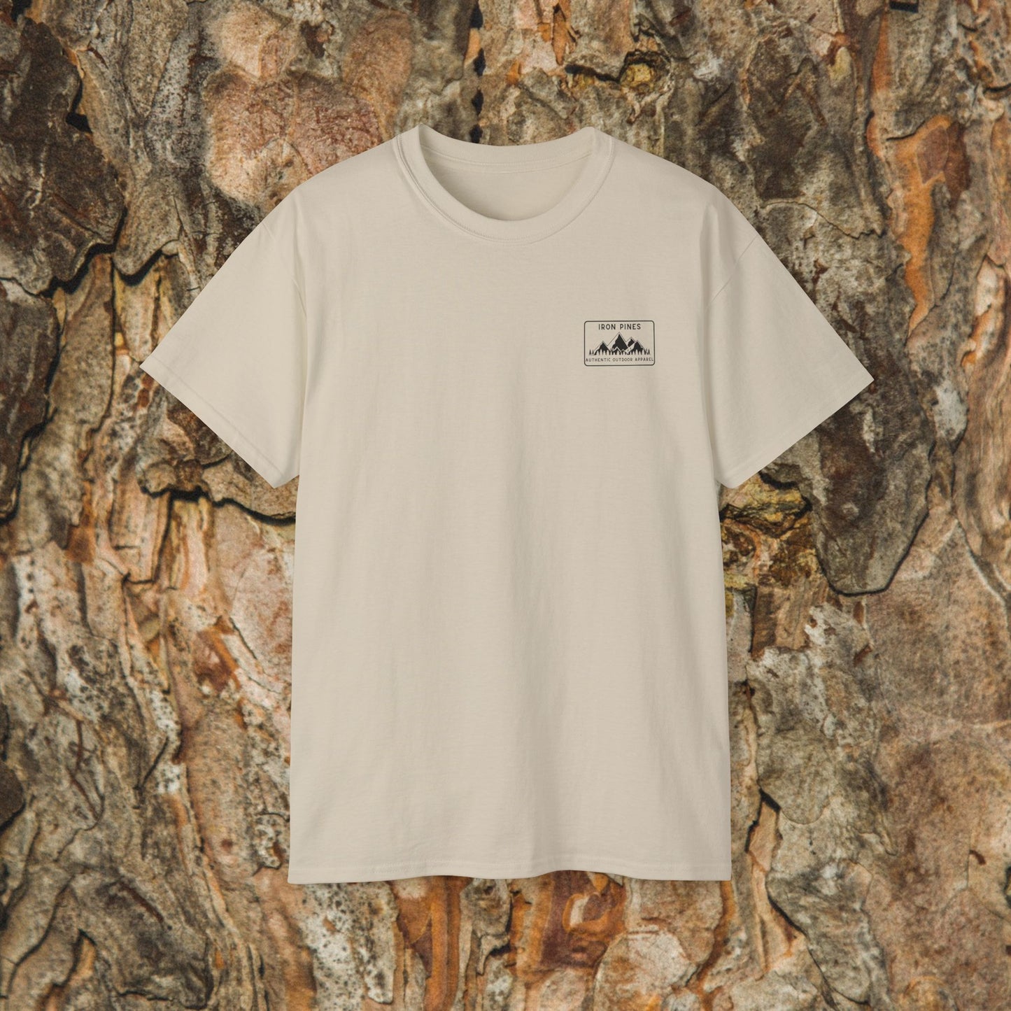The Iron Pines Public Lands in Public Hands Tee is an off-white, ethically sourced cotton hiking shirt with a small mountain graphic and text on the left chest, shown against textured tree bark.