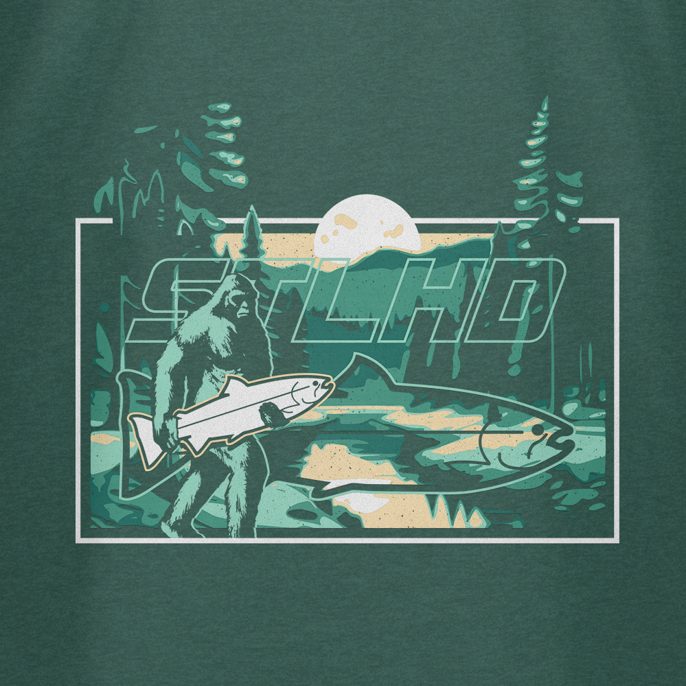 The STLHD GEAR Lost Forest T-Shirt features a playful Bigfoot holding a fish design, perfect for nature lovers who want to add adventurous style to their wardrobe.
