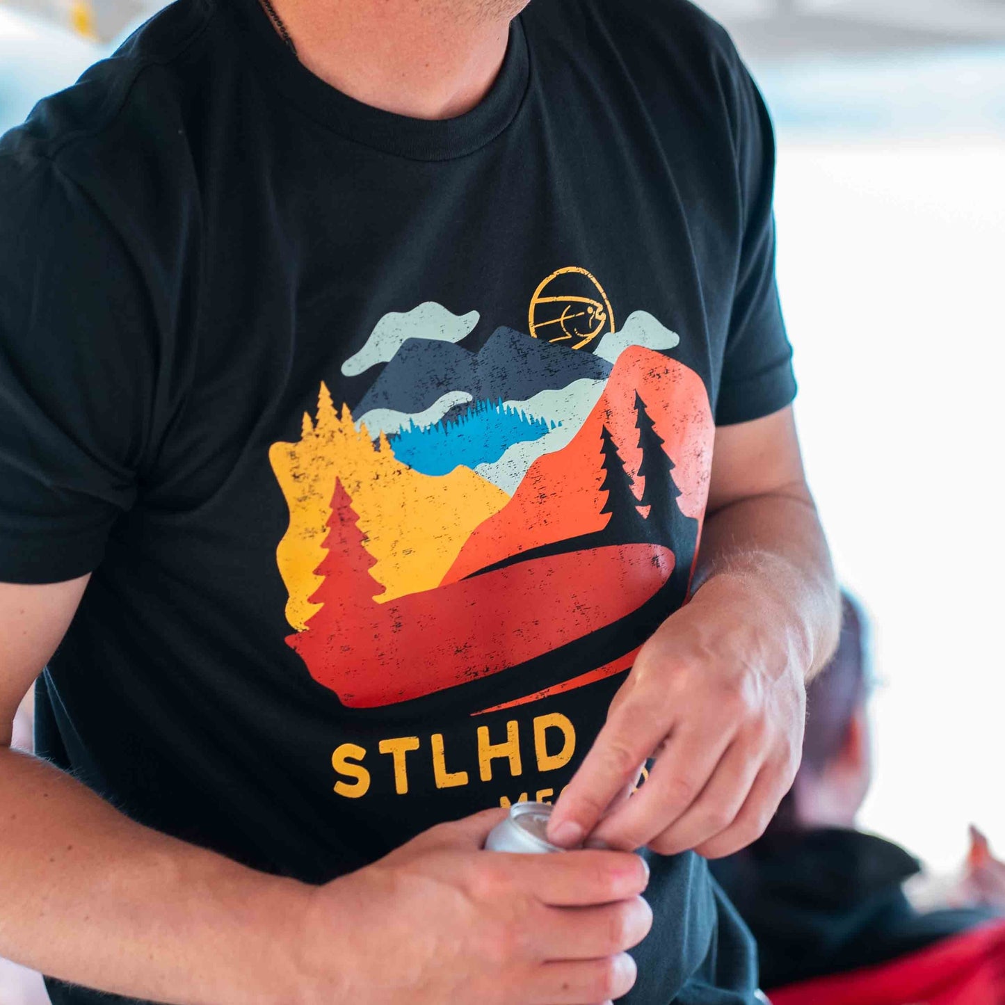 Person wearing a black t-shirt with a colorful Journey graphic and 'STLHD GEAR MFG CO.' text
