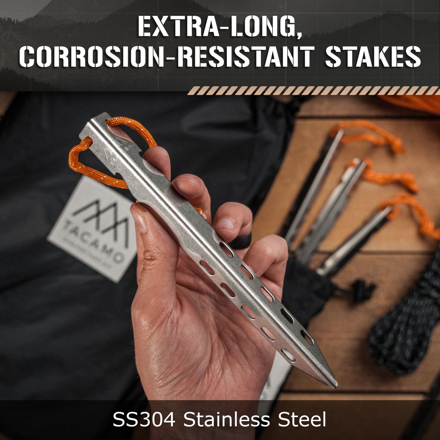 A hand holds a TITAN Survival TACAMO® Bushcraft Reflective Shelter Tarp SS304 stainless steel stake with orange cord. Extra-long, corrosion-resistant stakes, carrying bag, and rope for tarp setups are blurred in the background.