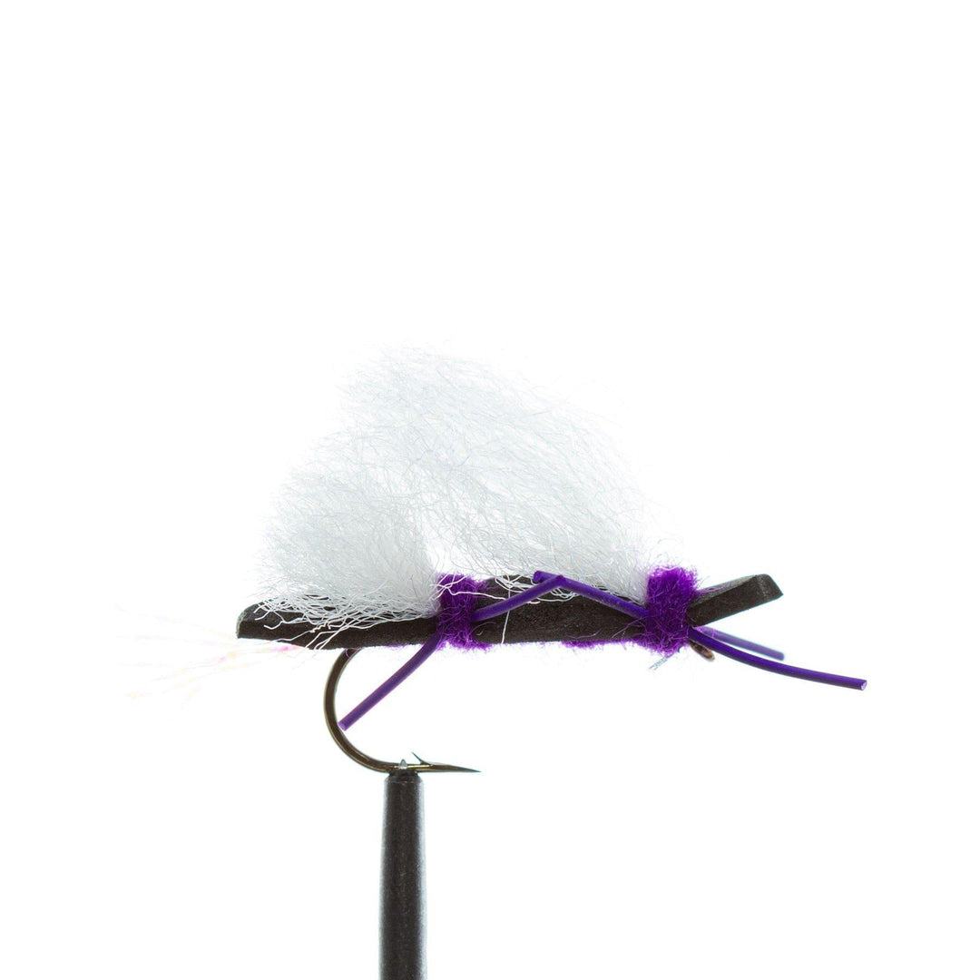 A close-up of a black hook, black and purple dry fly from the JHFLYCO Loaded Foam Fly Box – Standard Dry Fly Assortment by Jackson Hole Fly Company, featuring white synthetic fibers and a small tail on a plain white background.