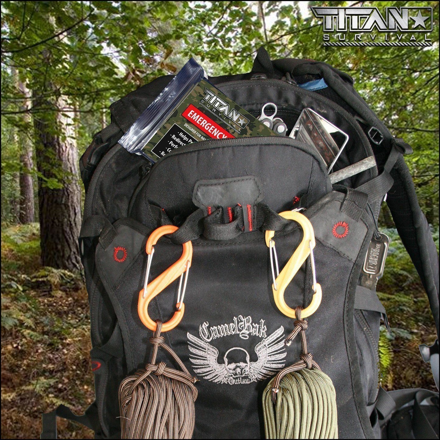 A black backpack with carabiners, paracord, and survival gear sits open in a forest. Emergency supplies, scissors, and a TITAN Survival Mylar Emergency Blanket 5-Pack (52 x 82) are visible among the trees in the background.