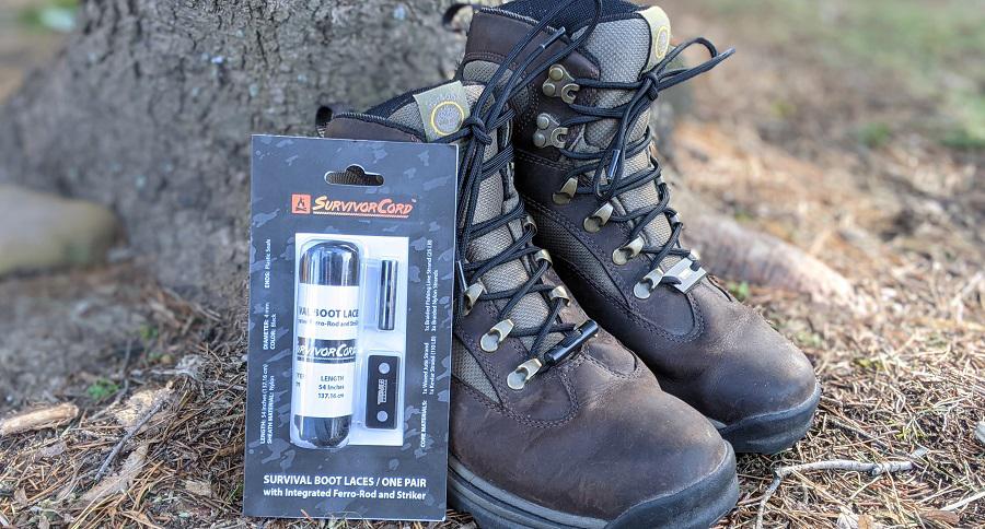 A pair of sturdy brown hiking boots rests by a tree. In front, TITAN Survival’s SurvivorCord® Boot Laces—featuring a firestarter, Kevlar, and fishing line—awaits among pine needles and grass for your essential outdoor upgrade.