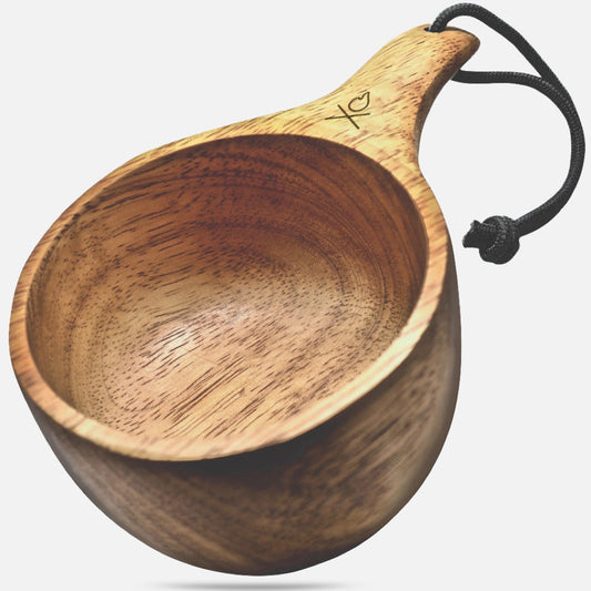 The Überleben Lore – Oversized Hardwood Kuksa features a handcrafted, smooth finish, short handle with simple heart and X design, and a black cord looped through the handle.
