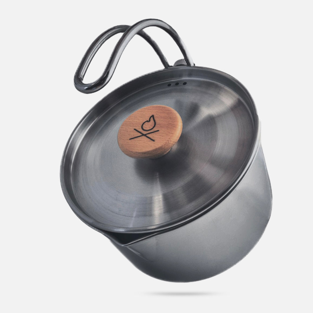 The Überleben Kessel – The Minimalist Cook Pot by Überleben is a stainless steel ultralight pot with a wooden heart-and-XO engraved lid handle, unique curved metal handle, and spout—perfect for backcountry camping, shown against a plain white background.
