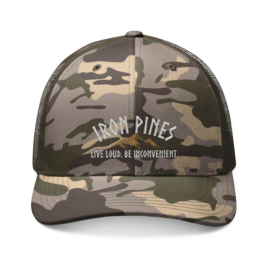 The Be Inconvenient Camo Trucker Hat by Iron Pines, available from Printify, features mesh backing, a snapback fit, embroidered Iron Pines above a mountain graphic, and the bold phrase Live Loud. Be Inconvenient.—perfect for adventurers.