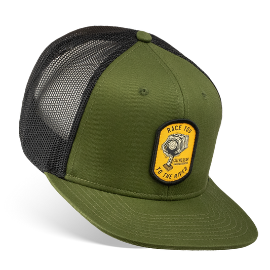 The STLHD Race Ya Flat Bill Trucker Hat by STLHD GEAR is olive green and black with a breathable mesh back, yellow patch with bike crank, “RACE YOU TO THE RIVER” text, and an adjustable snapback for the perfect fit.