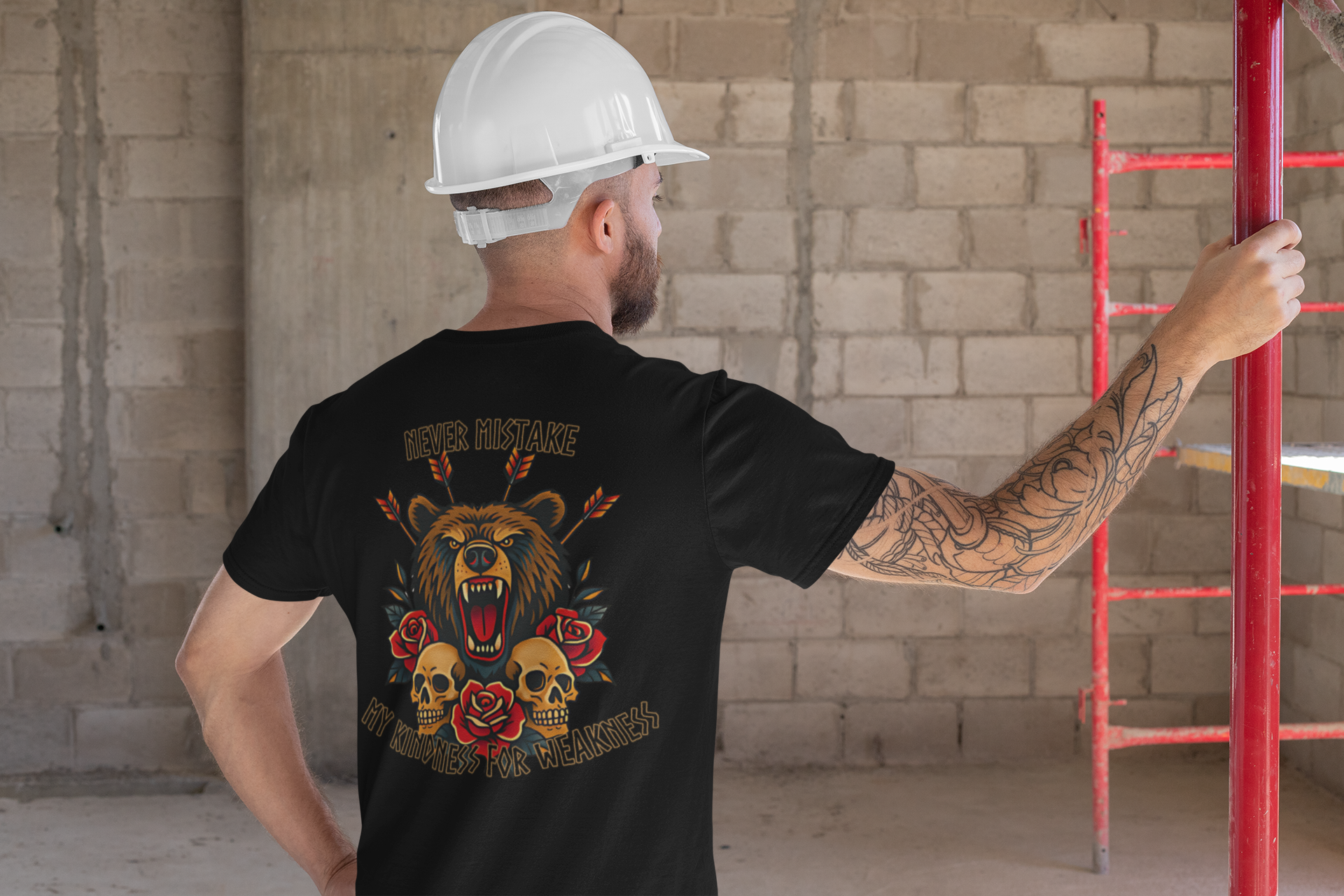 A man in a white hard hat and black Printify Never Mistake My Kindness For Weakness Tee stands at a construction site. The graphic features a roaring bear, roses, skulls, arrows, and the phrase Never mistake my kindness for weakness.