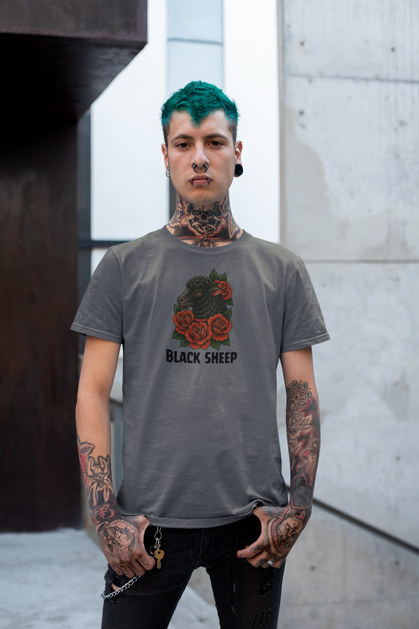 A person with teal hair, piercings, and tattoos stands outdoors wearing Printifys Black Sheep Tee—a grey softstyle shirt with red roses, a black sheep graphic, and the words BLACK SHEEP.