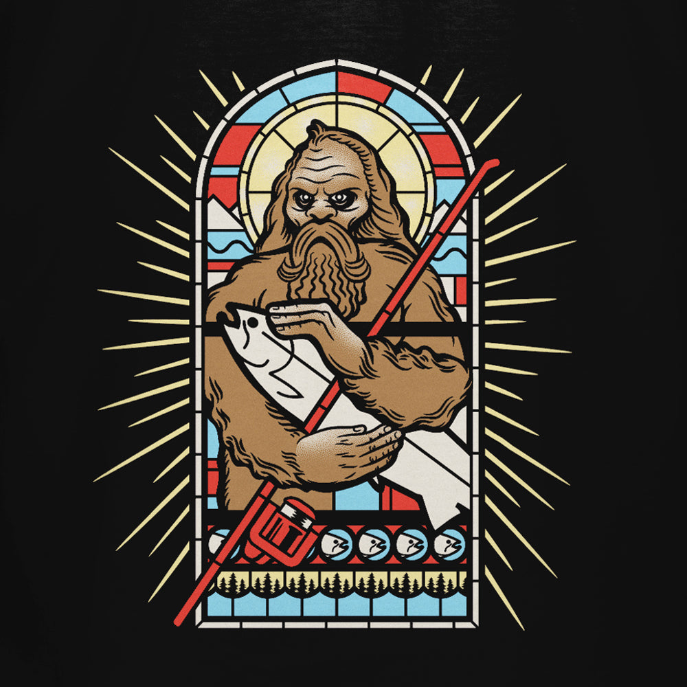 The STLHD Men’s Saint Sasquatch Black T-Shirt by STLHD GEAR features a stained glass-style Bigfoot with a scroll and red staff, glowing halo, and vibrant colors on a black background, inspired by the comfort of premium breathable fishing shirts.