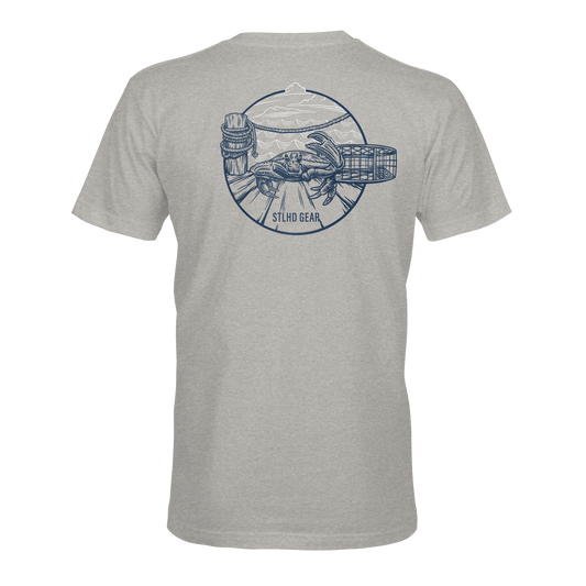 The STLHD Mens Crabby T-Shirt by STLHD GEAR is a heather gray fishing tee featuring a blue back graphic with hands holding fishing gear, a fish, basket, and scenic mountains. Enjoy breathable comfort. SILO GEAR is printed below the design.