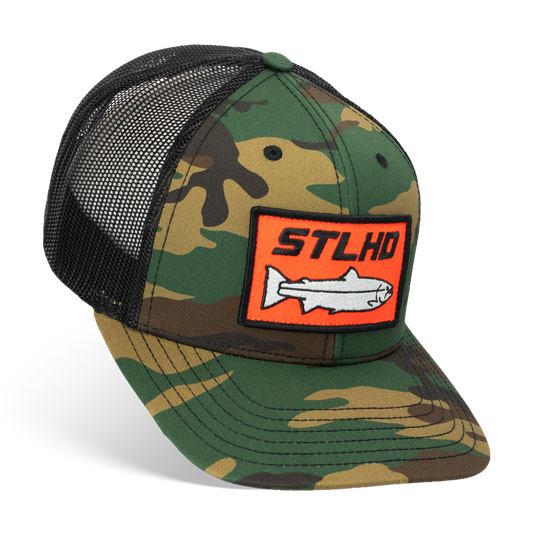 The STLHD GEAR Camo Snapback Trucker Hat features a black mesh back, adjustable snap closure, and a front patch with an orange border, STLHD lettering, and a white fish—ideal for your next fishing trip.