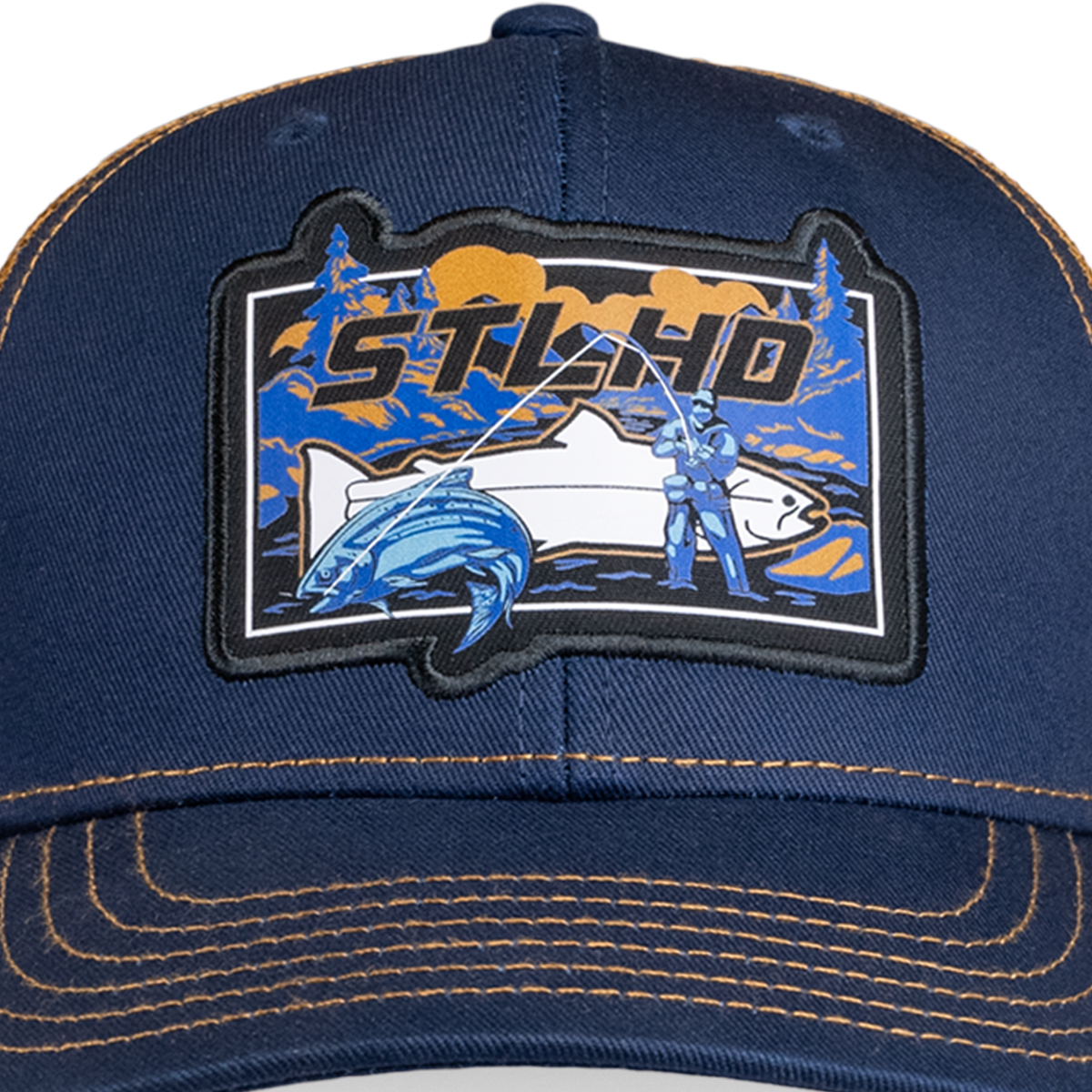 A close-up of the STLHD GEAR Let’er Rip Trucker Hat, a navy blue adjustable snapback with orange stitching and a colorful fishing patch featuring a person, large fish, trees, and STLHD in bold letters.