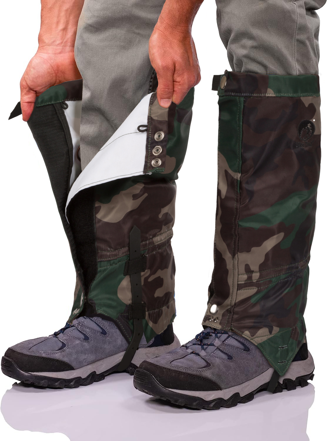 A person in gray pants and outdoor shoes adjusts Pike Trail All-Season Waterproof Leg Gaiters—camouflage-patterned, secured with buttons and Velcro around the lower legs—for trail, hunt, and more.