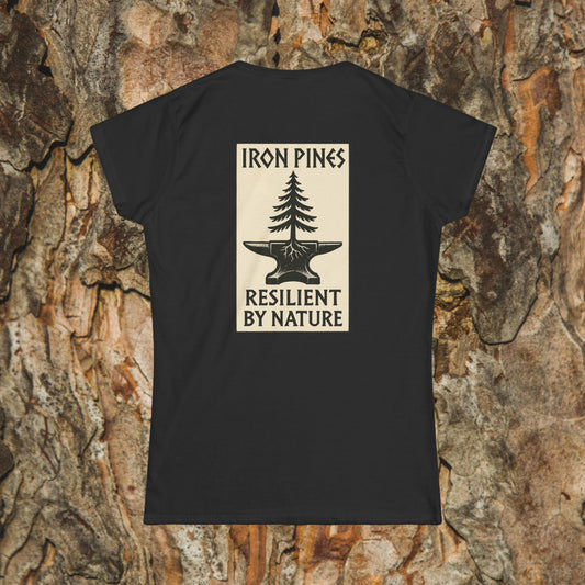 The Iron Pines Woman’s Tee by Printify is a black softstyle shirt featuring a beige pine tree and anvil graphic with “IRON PINES RESILIENT BY NATURE” on the back, shown against tree bark.