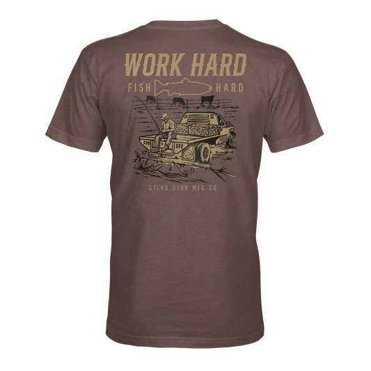 The STLHD Rancher T-Shirt by STLHD GEAR features a graphic of a person fishing by a car, “WORK HARD, FISH HARD” with a fish silhouette above, and STLHD GEAR MFG CO. below—a breathable tee for those who live by the motto.