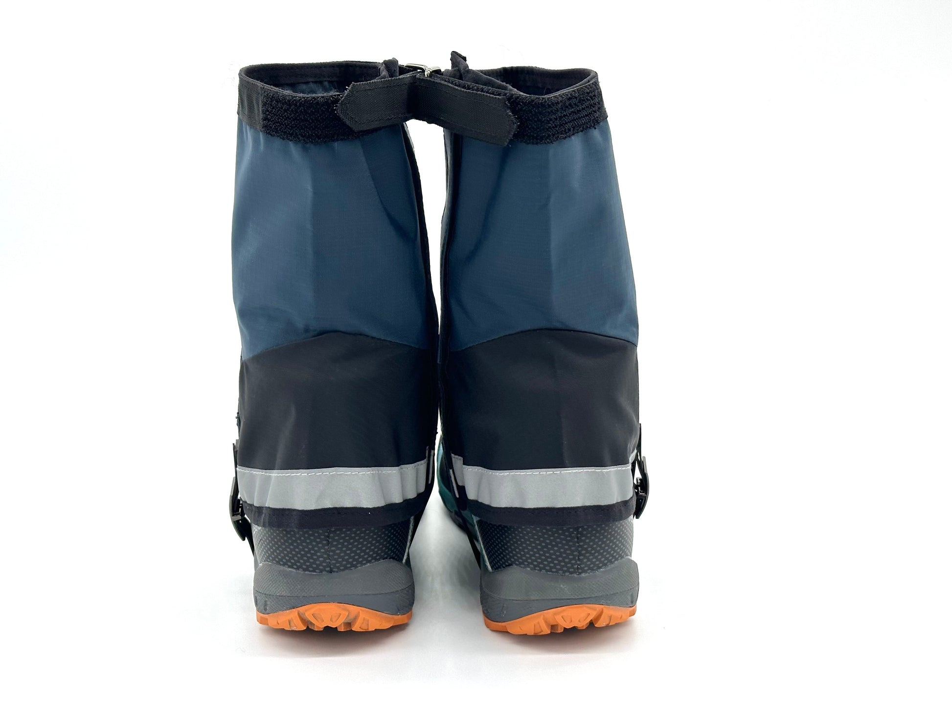 The Pike Trail Mid-Length Gaiter (Small/Medium Adjustable Fit) by Pike Trail, shown in black and dark blue with gray reflective stripes, is displayed secured over shoes with orange soles, photographed from the back on a white background.