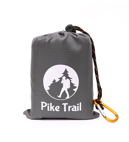 The Pike Trail Pocket Blanket – Compact, Rugged, Always Ready – comes in a gray drawstring bag with the Pike Trail logo and is attached to an orange carabiner with black rope—ideal for carrying on any adventure.
