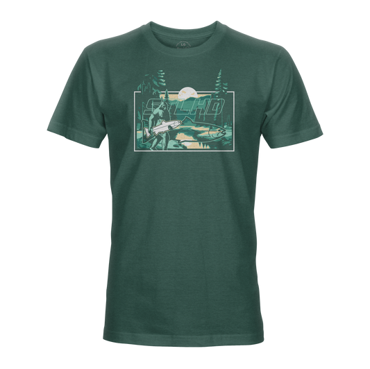 The STLHD Lost Forest T-Shirt by STLHD GEAR is a dark green outdoor tee with a mountain, trees, river, and angler scene. “Macho” stands out above the art—ideal for fans of outdoor adventure apparel.