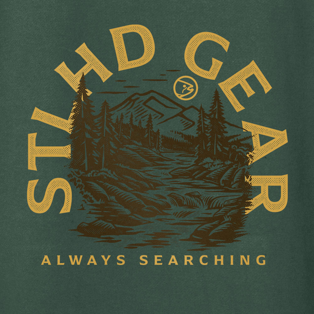 Illustration of a forested mountain with river, framed by bold yellow STLHD GEAR text. Below: ALWAYS SEARCHING. Show your style and stay ready for any adventure in the durable STLHD Mountain View Premium Hoodie from STLHD GEAR.
