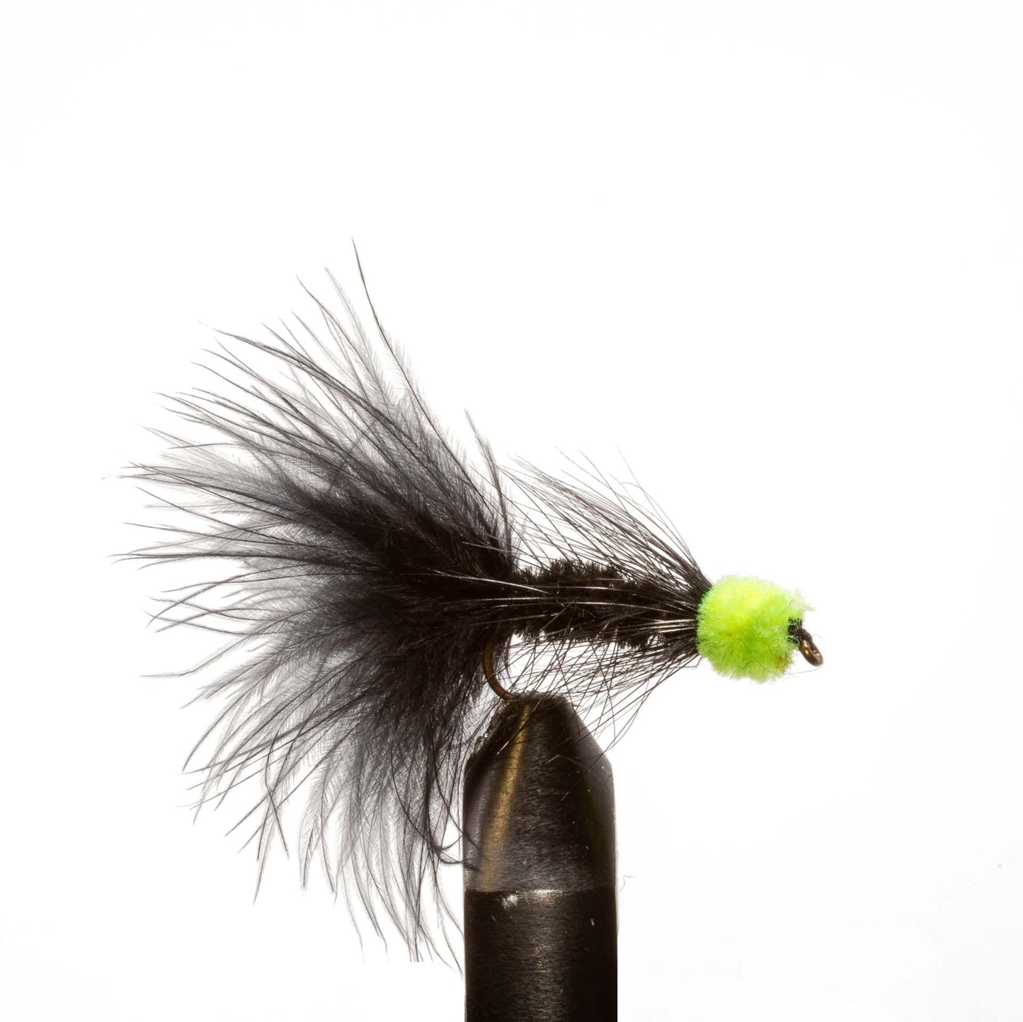 A close-up of a black woolly bugger fly with a bright green bead head, held in a vise against a white background—part of the JHFLYCO Steelhead Fly Box 24-piece collection by Jackson Hole Fly Company. Ideal for your next steelhead outing.