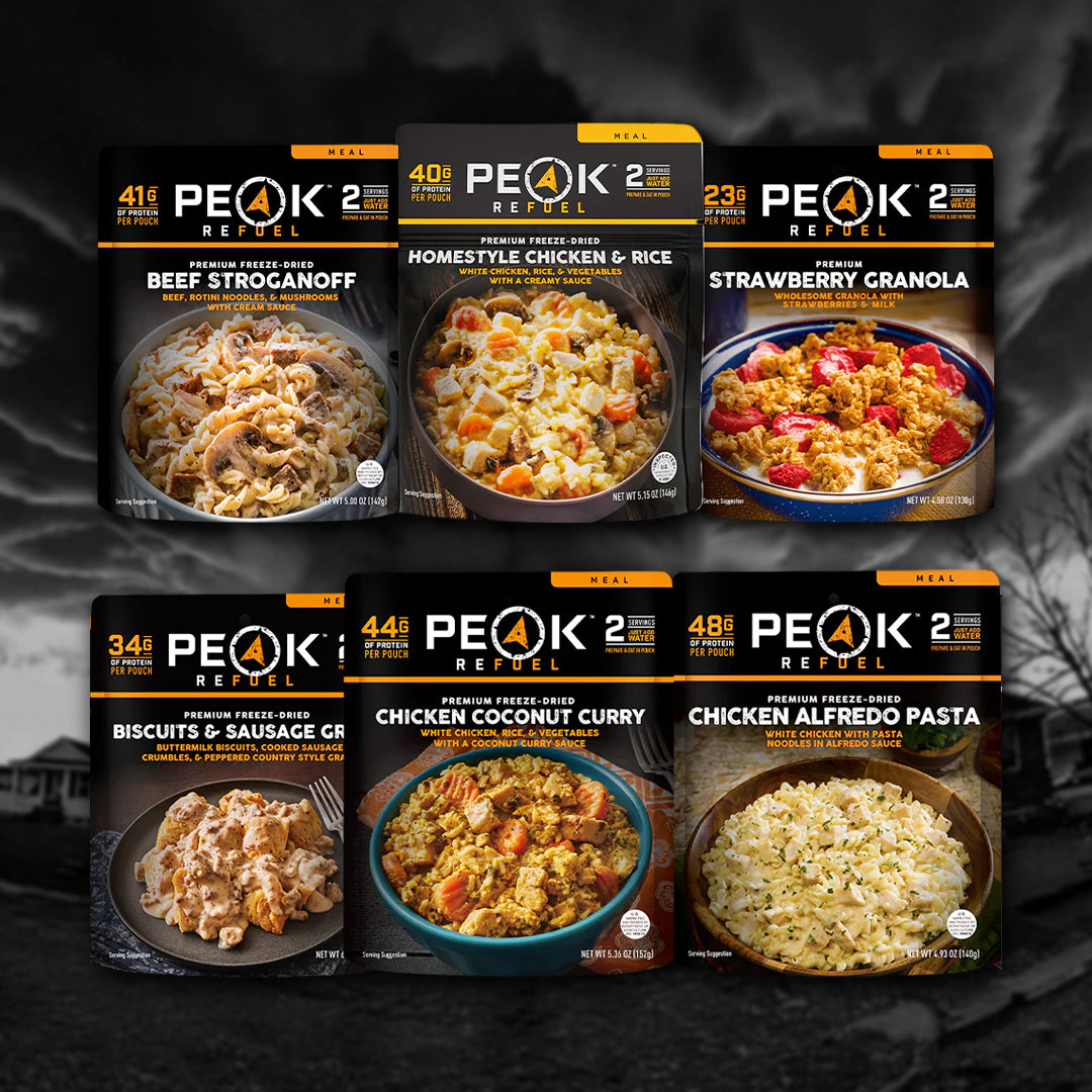 Six Entropy Survival Alpine Survival Pack 2.0 freeze-dried meals, including high-protein options like Beef Stroganoff and Chicken Alfredo Pasta, are displayed against a dark, cloudy background.